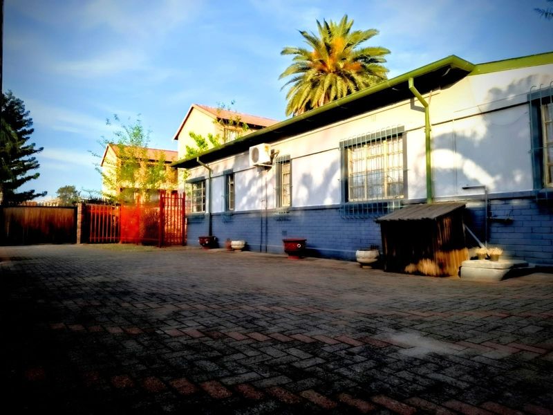 A paved rear courtyard area featuring a single-story building exterior with security bars on windows and an external air conditioning unit.