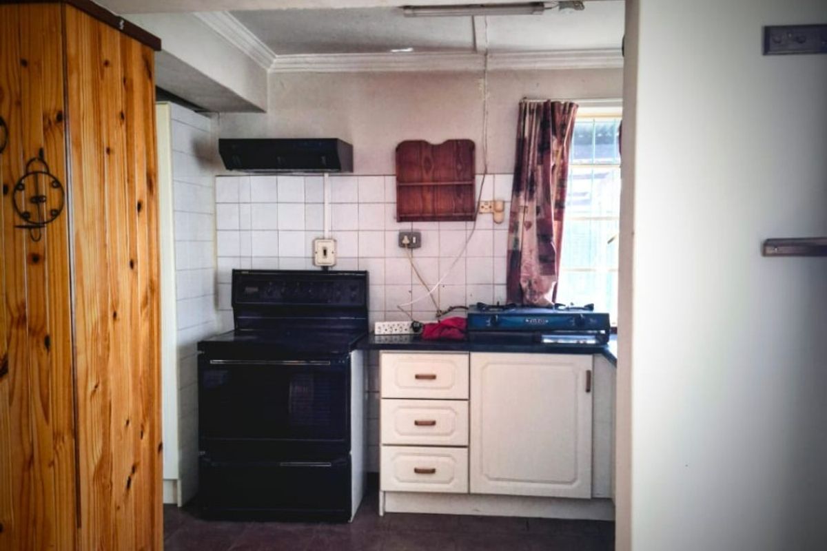 A dated kitchen featuring tiled backsplash, built-in cabinetry, and a freestanding stove, requiring modernization to improve functionality and aesthetic appeal.