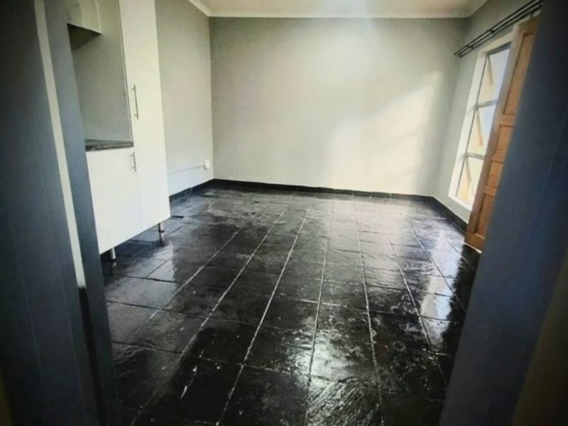 An empty kitchen space featuring dark stone tile flooring and built-in cabinetry, offering a blank canvas for potential renovation or styling.