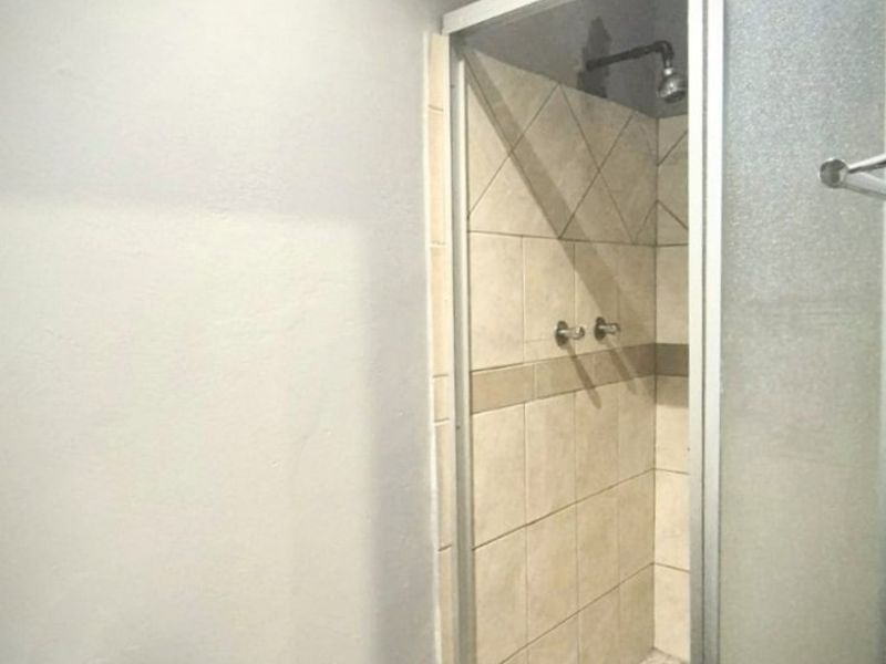 A functional bathroom featuring a glass-enclosed shower with tiled walls and flooring, providing a clean and practical space.
