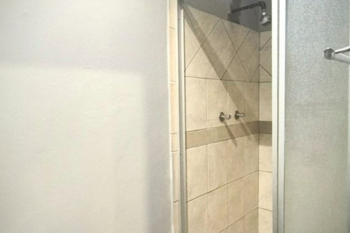A functional bathroom featuring a glass-enclosed shower with tiled walls and flooring, providing a clean and practical space.