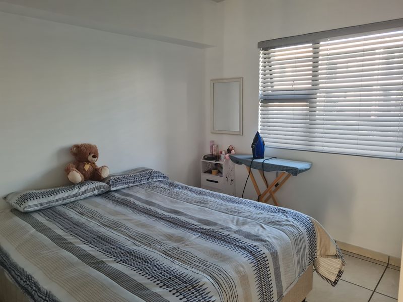 A functional bedroom featuring tiled flooring and venetian blinds, providing a neutral base for personalization.