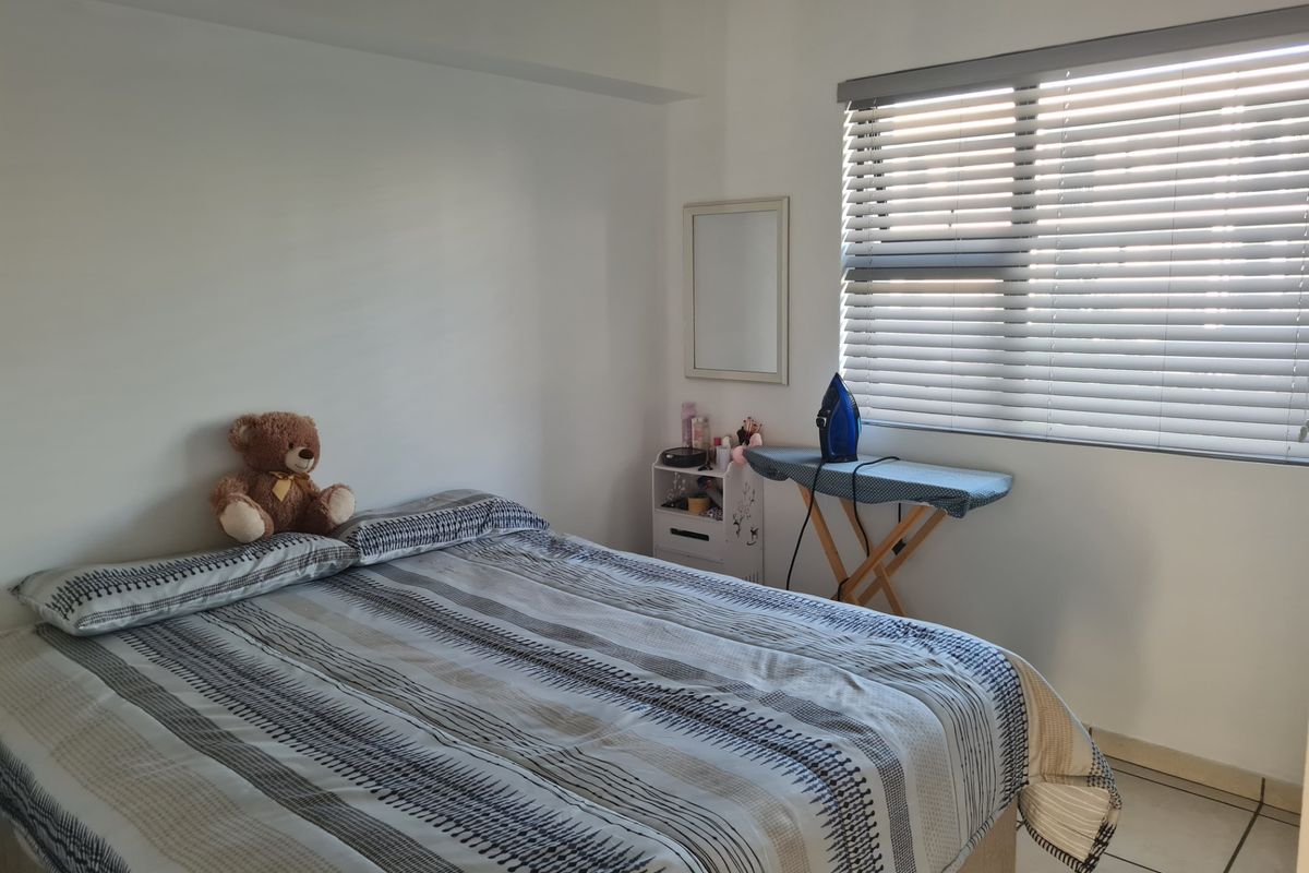 A functional bedroom featuring tiled flooring and venetian blinds, providing a neutral base for personalization.