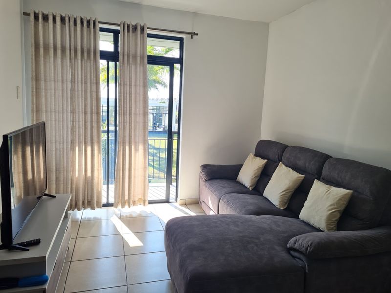 A bright living room featuring tiled flooring and a sliding glass door that provides access to an outdoor area.