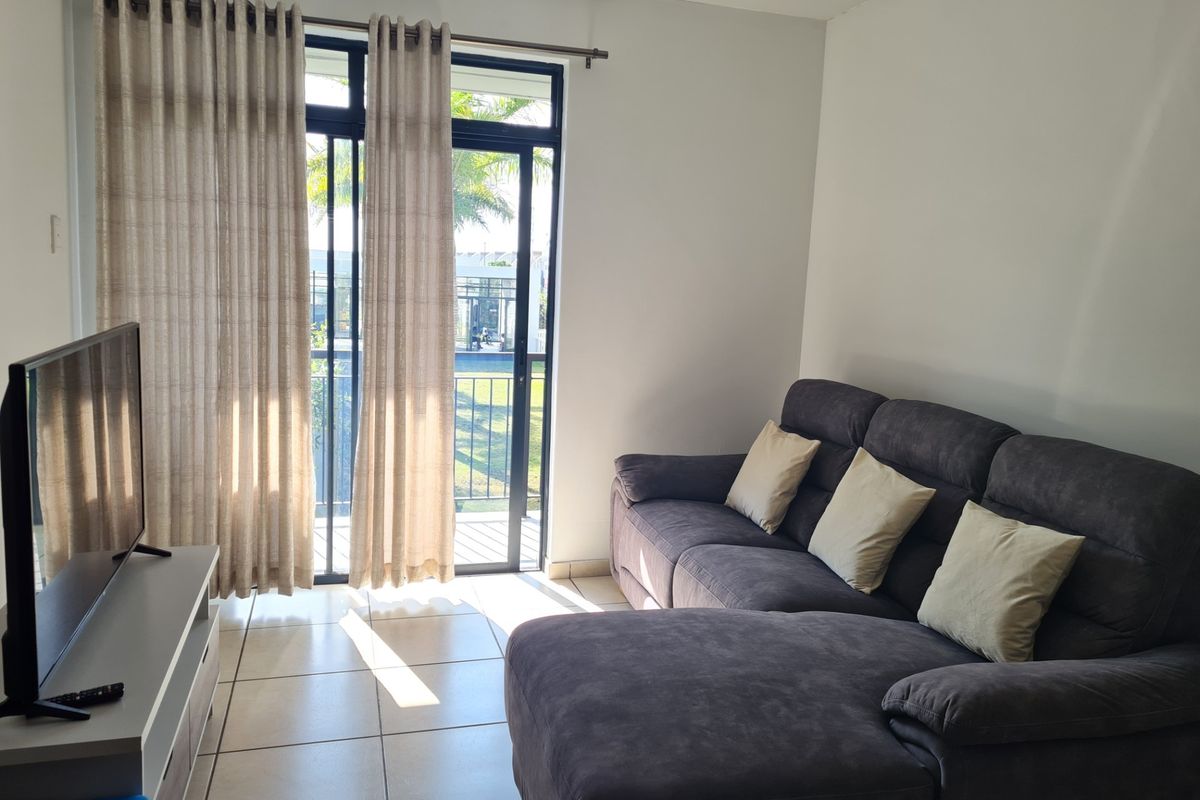 A bright living room featuring tiled flooring and a sliding glass door that provides access to an outdoor area.