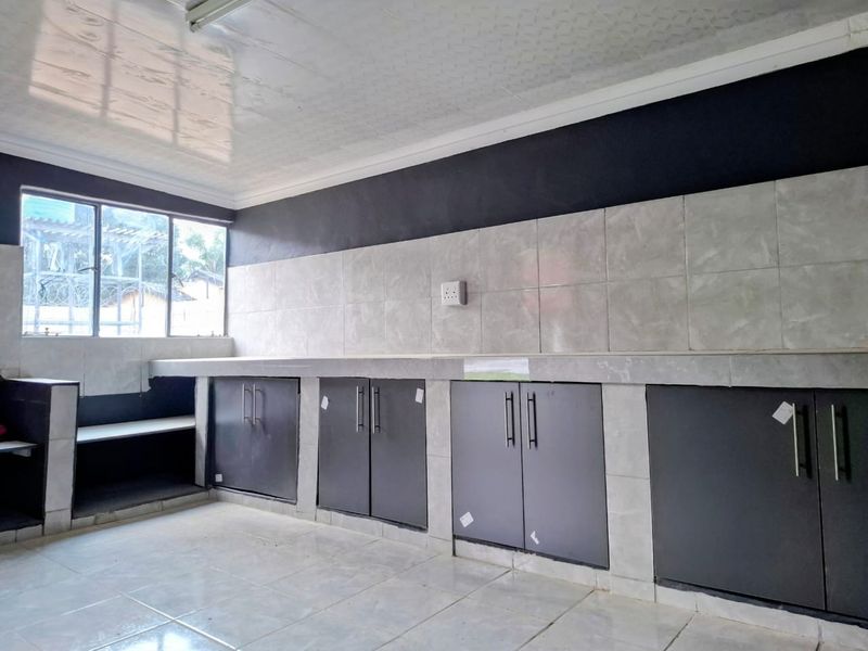 A functional kitchen space featuring tiled countertops, built-in cabinetry, and a tiled backsplash, offering a clean and neutral foundation for further customization.