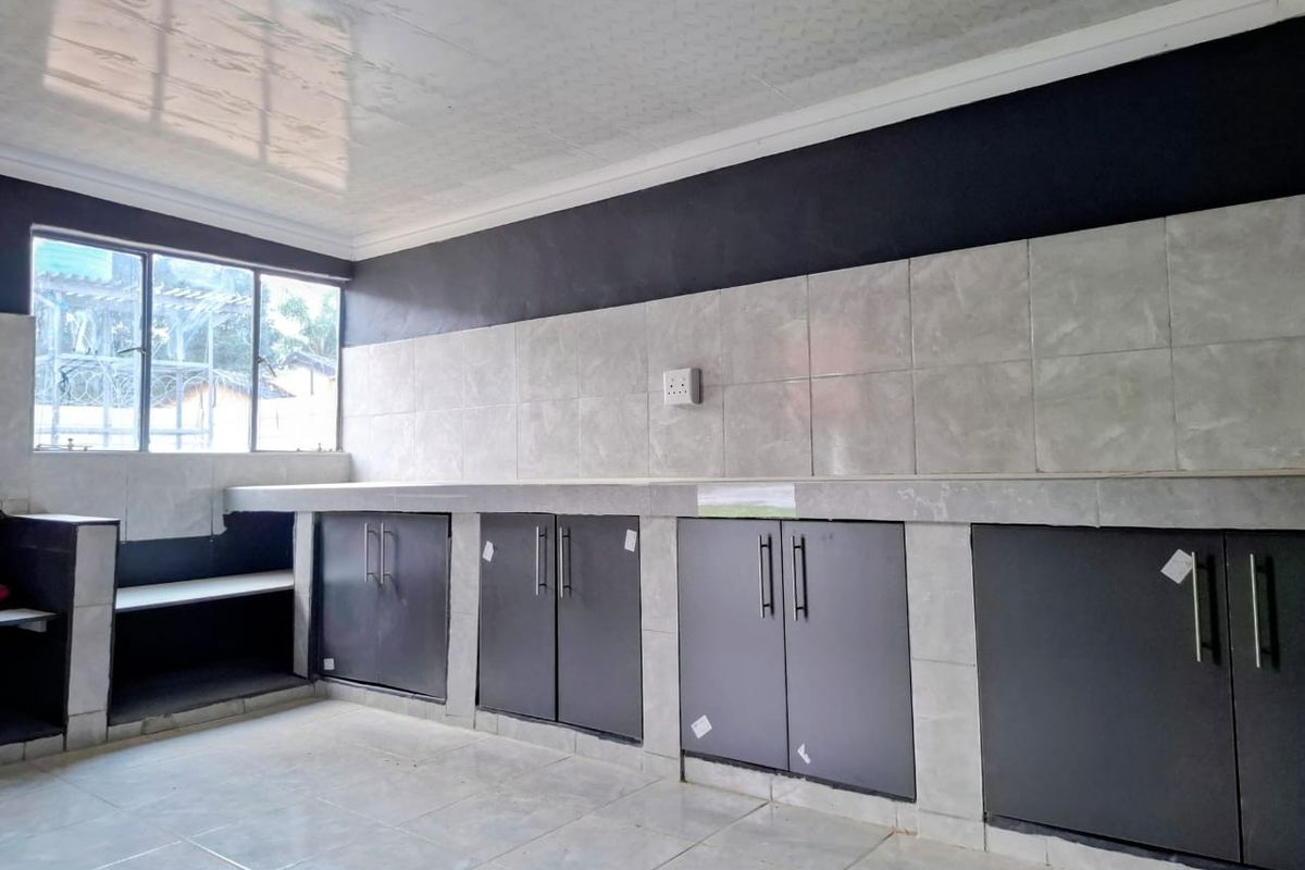 A functional kitchen space featuring tiled countertops, built-in cabinetry, and a tiled backsplash, offering a clean and neutral foundation for further customization.