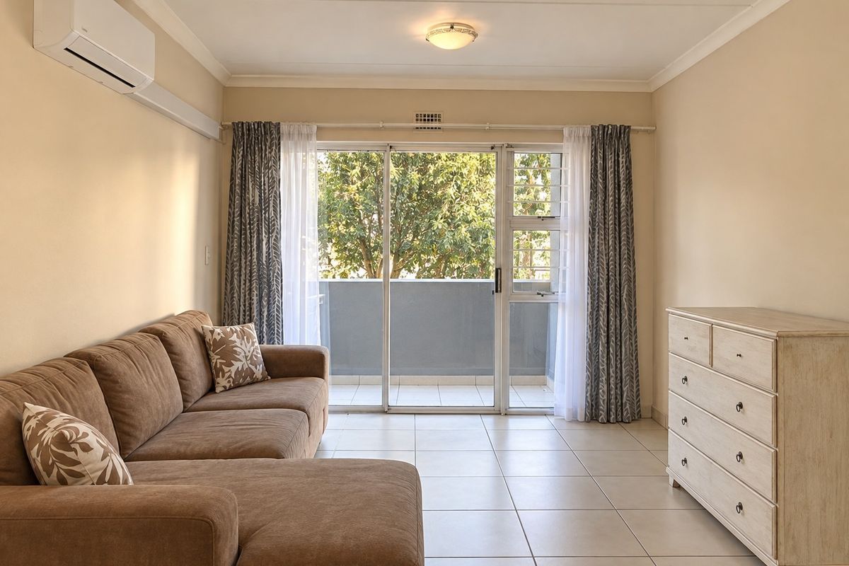 A bright living room featuring tiled flooring, a split-system air conditioner, and a sliding glass door providing access to a balcony.