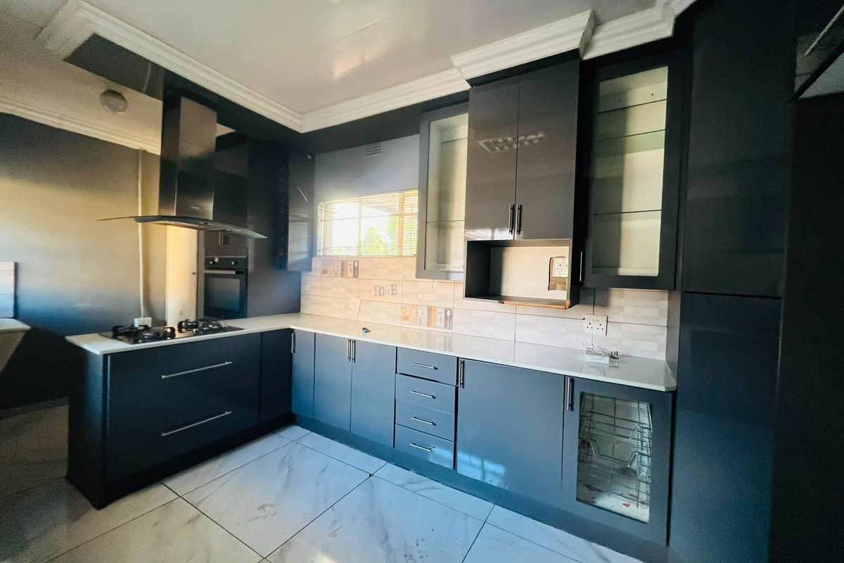 Modern kitchen featuring sleek dark cabinetry, stone countertops, integrated gas hob, extractor fan, and high-quality tiled flooring.