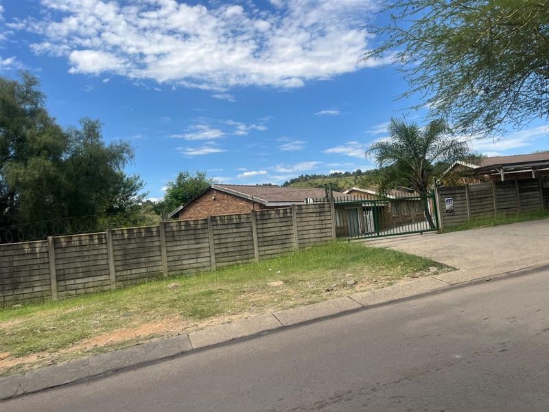 Street view of the property featuring a brick facade, tiled roof, and a secure gated entrance with a precast concrete boundary wall.