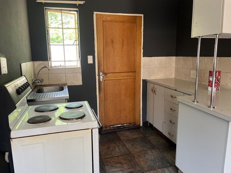 A functional kitchen featuring a built-in electric stove, stainless steel sink, tiled backsplash, and ample cabinetry with laminate countertops.