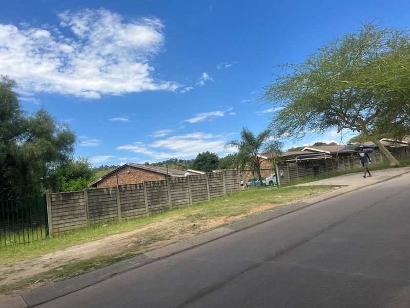 Street view showing the exterior boundary wall and perimeter fencing of the apartment complex from the adjacent road.