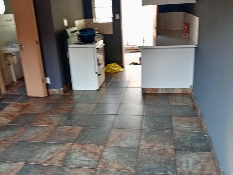 A functional kitchen area featuring tiled flooring, built-in cabinetry, and a freestanding stove, offering a blank canvas for potential renovation and modernization.