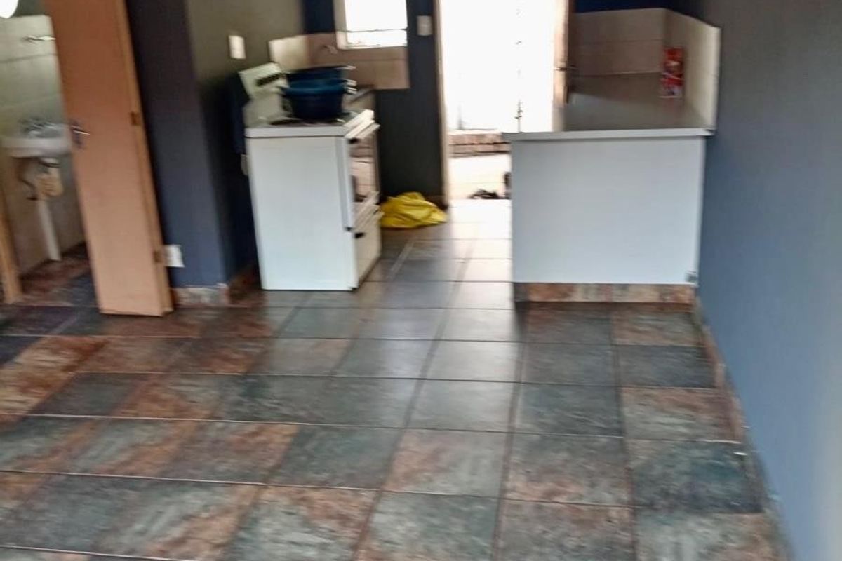 A functional kitchen area featuring tiled flooring, built-in cabinetry, and a freestanding stove, offering a blank canvas for potential renovation and modernization.