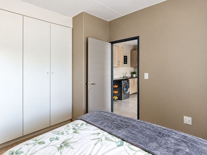 A well-maintained bedroom featuring a large built-in wardrobe and direct access to an adjacent kitchen or utility area.