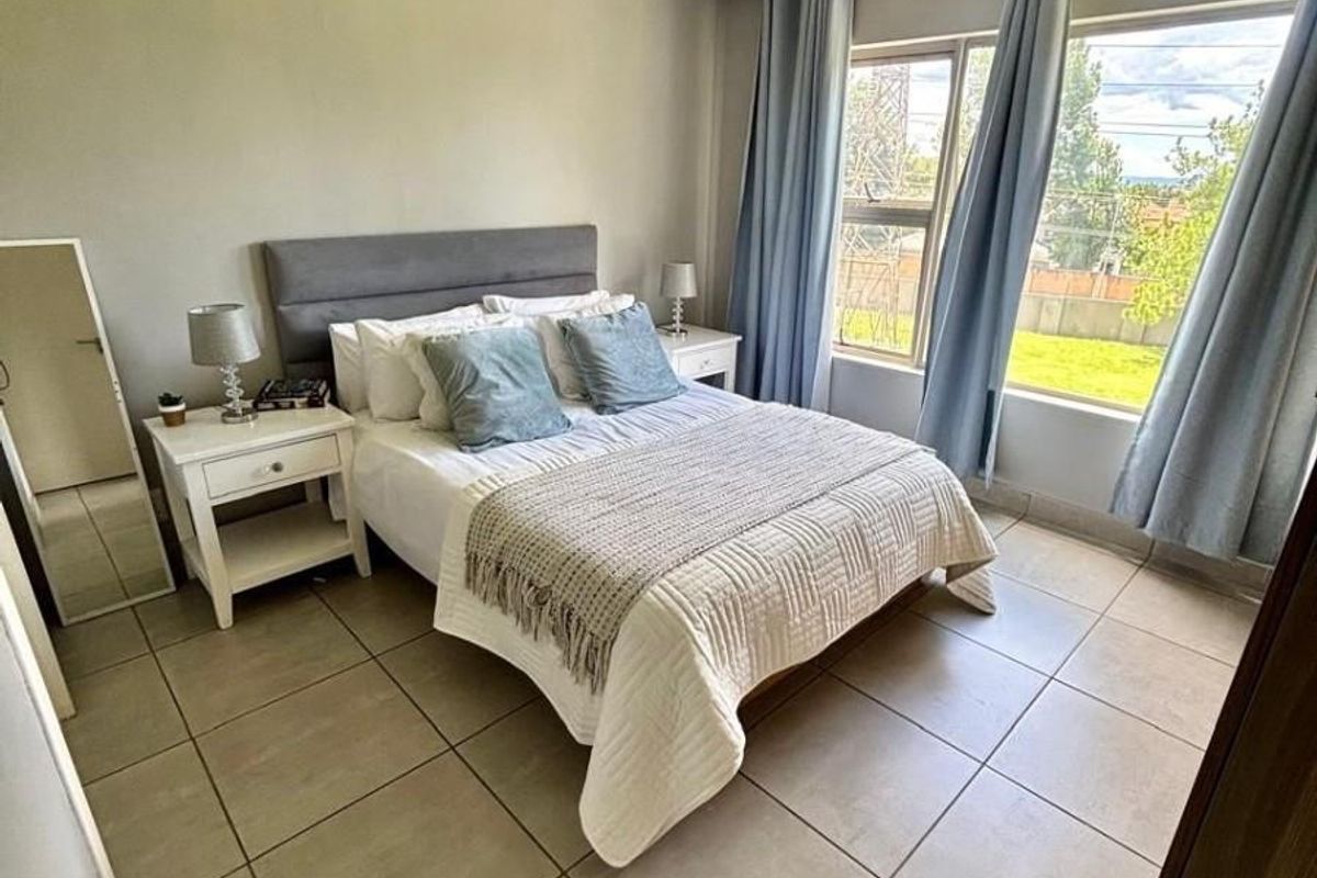 A well-maintained bedroom featuring neutral tiled flooring, recessed ceiling lighting, and large windows that provide ample natural light.