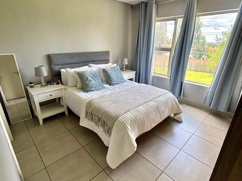 A well-maintained bedroom featuring neutral tiled flooring, recessed ceiling lighting, and large windows that provide ample natural light.