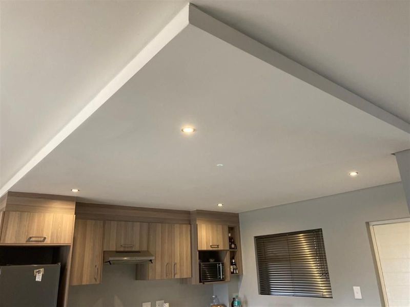 Modern kitchen area featuring a distinctive drop ceiling with recessed lighting, wood-finish cabinetry, and an integrated extractor fan.