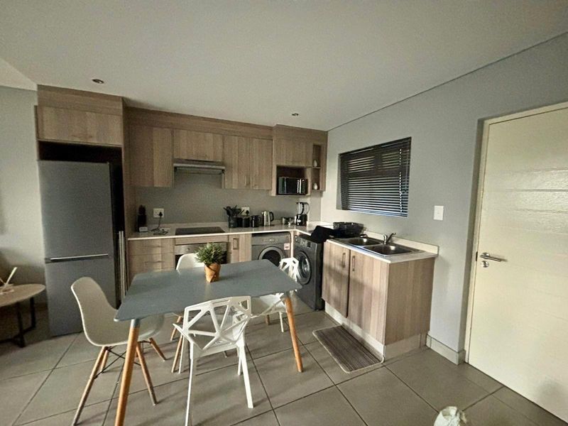 Compact kitchen featuring light wood-finish cabinetry, laminate countertops, integrated appliances, and tiled flooring, offering a functional and modern layout.