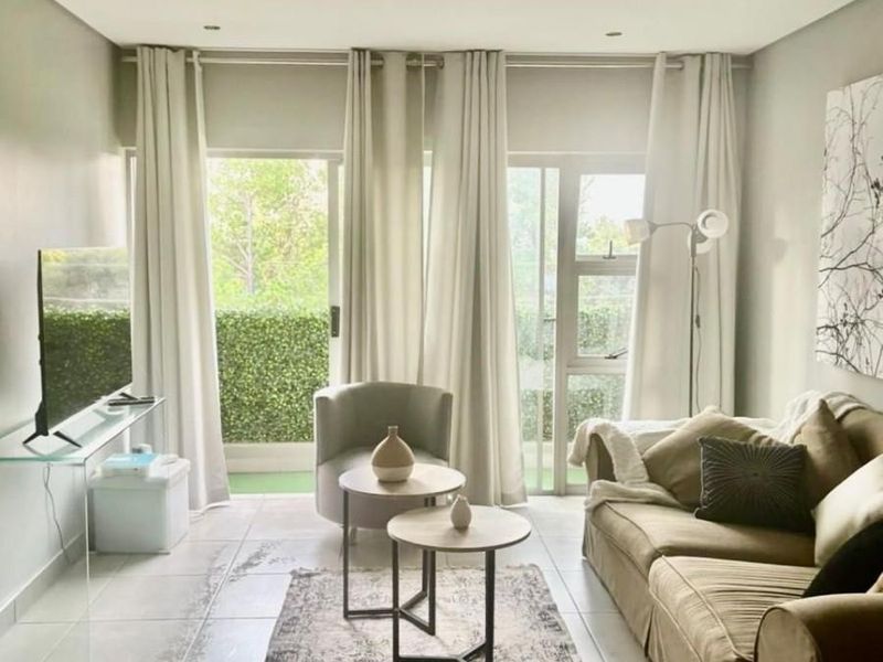 A bright living room featuring tiled flooring and large sliding glass doors that provide access to an outdoor patio area.