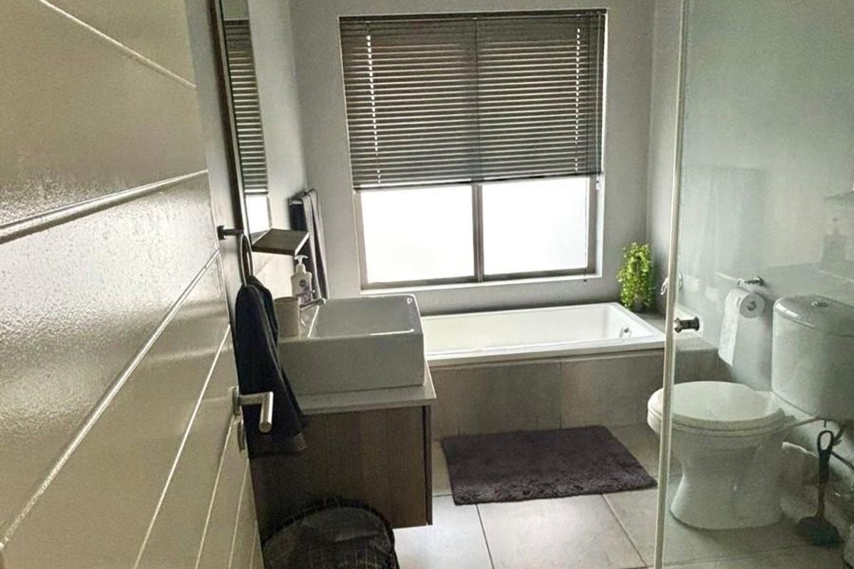 Modern bathroom featuring a built-in vanity with vessel sink, a glass-enclosed shower, and a built-in bathtub with neutral floor tiling.