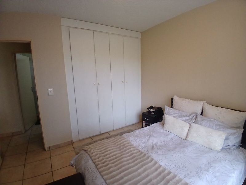 A bedroom featuring built-in cupboards and tiled flooring, providing a functional space with neutral wall finishes.
