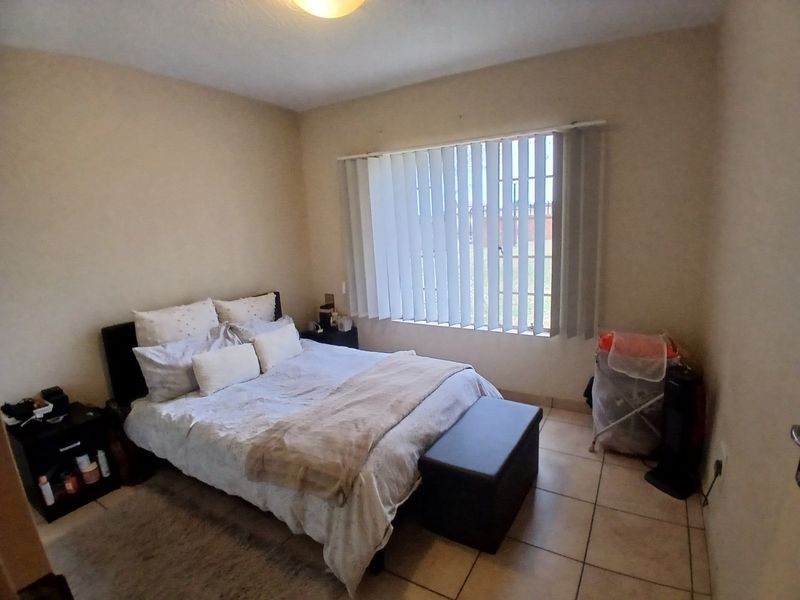 A standard bedroom featuring tiled flooring and vertical window blinds, providing a functional and neutral space.