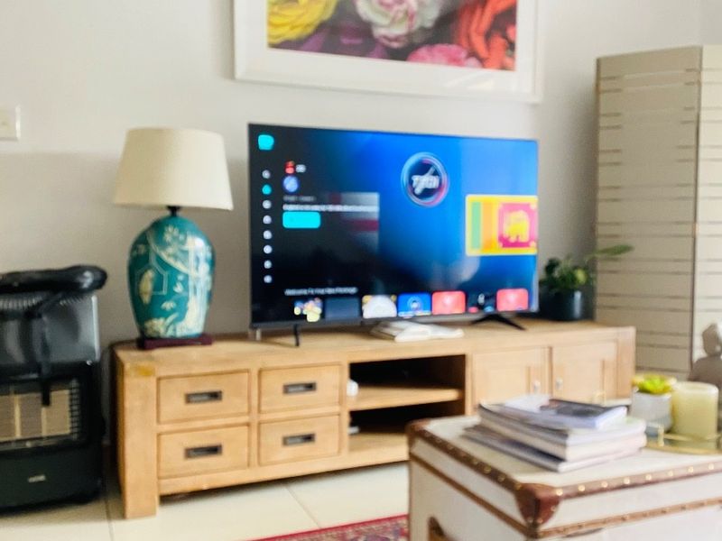 A living room area featuring tiled flooring and decorative coving, currently set up as a media space.