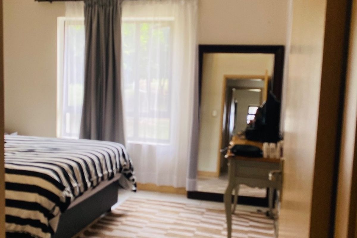 A bedroom featuring neutral walls, a ceiling light fixture, and built-in cupboard storage, offering a functional space with natural light.
