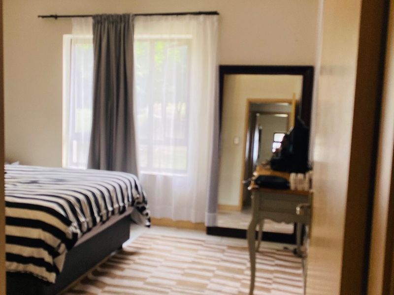 A bedroom featuring neutral walls, a ceiling light fixture, and built-in cupboard storage, offering a functional space with natural light.
