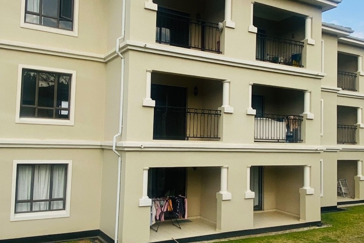 A multi-story apartment building exterior featuring stacked balconies with metal railings and neutral-toned facade finishes.