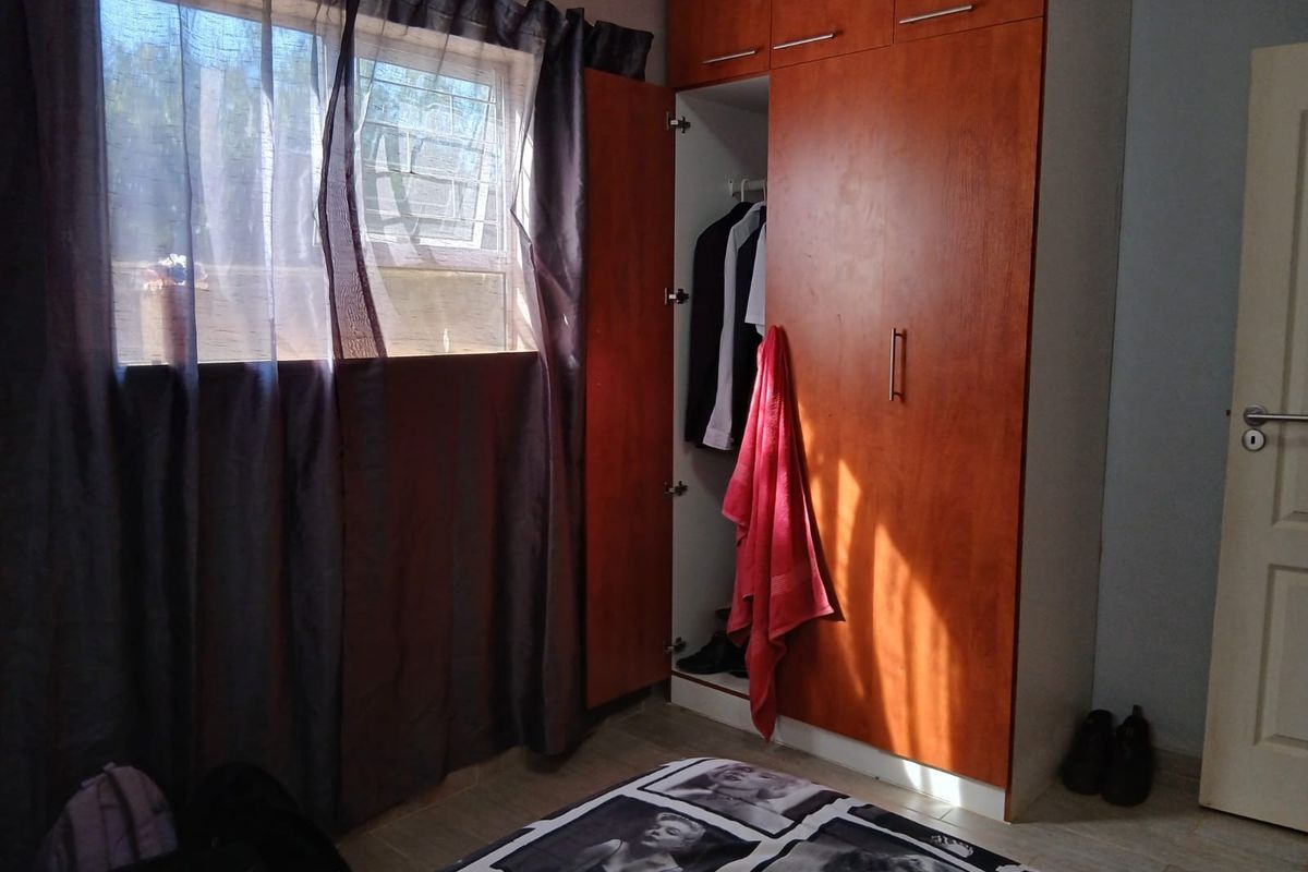 A bedroom featuring built-in wooden cupboards and tiled flooring, providing functional storage space within the room.