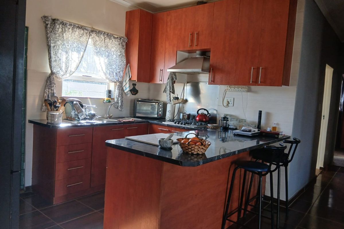 Functional kitchen featuring warm-toned built-in cabinetry, granite countertops, a gas hob, and a breakfast nook, providing a practical workspace for daily cooking.