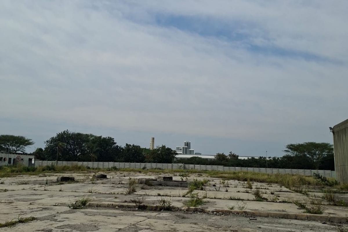 A large, vacant industrial concrete yard featuring a perimeter wall and significant surface wear, suitable for redevelopment or storage.