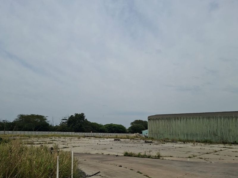 Expansive industrial yard featuring concrete paving and large metal-clad structure, suitable for storage or logistics operations.