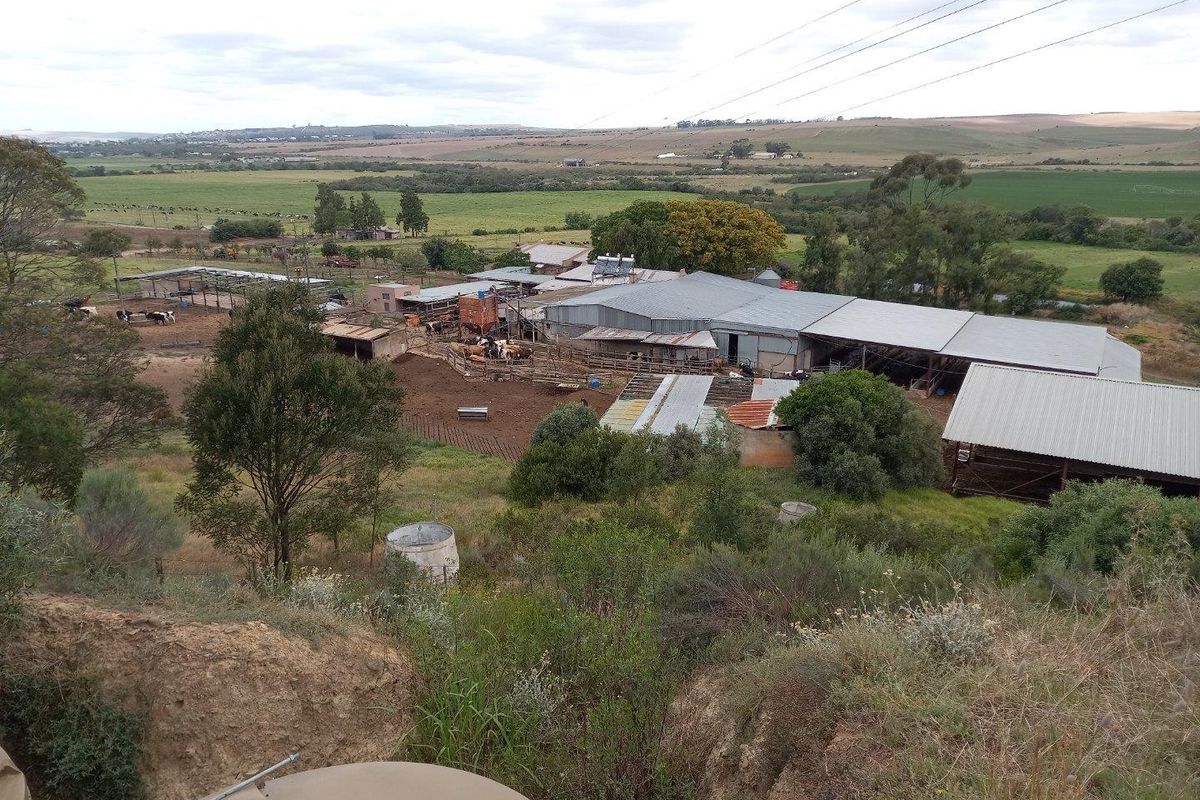 Aerial view of a working farm property featuring multiple outbuildings, livestock enclosures, and expansive rural landscape.