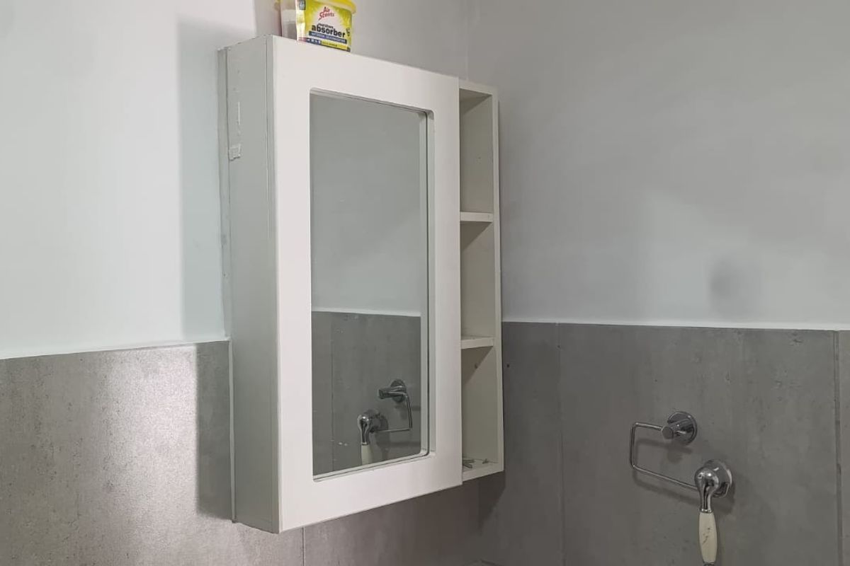 A functional bathroom space featuring a wall-mounted medicine cabinet and neutral grey wall tiling.