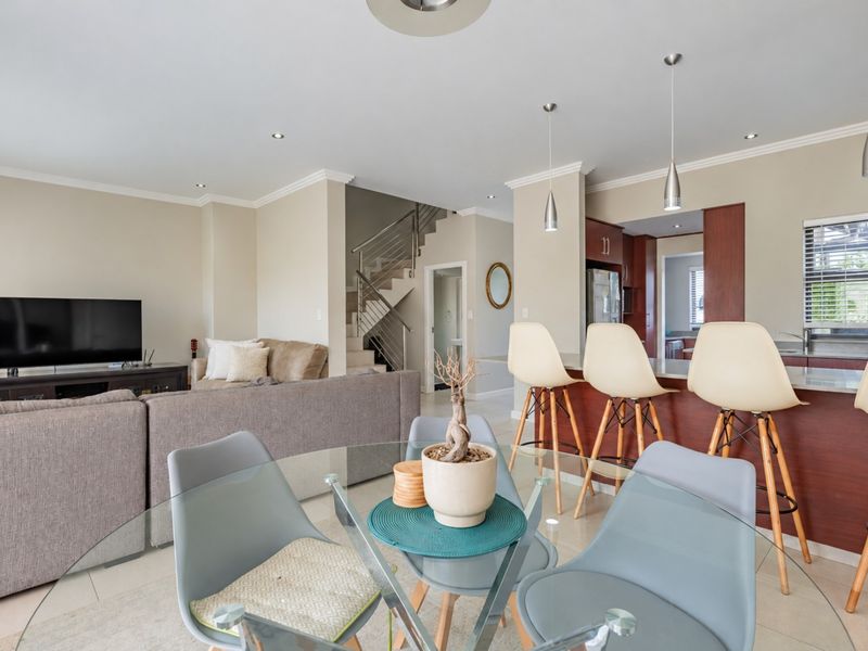 Spacious open-plan living and dining area featuring a modern kitchen with island, sleek cabinetry, and a staircase with a contemporary metal balustrade.