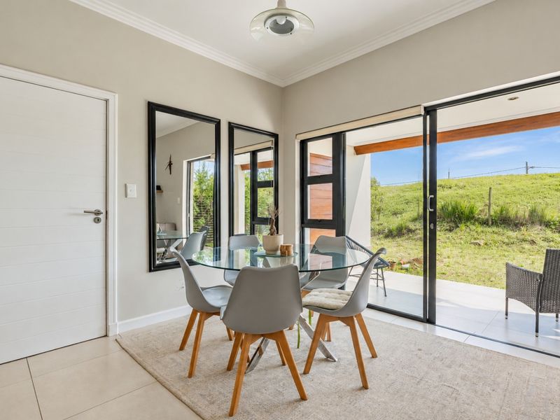 Bright dining area featuring large sliding glass doors that open onto a patio, with neutral tiled flooring and modern finishes.