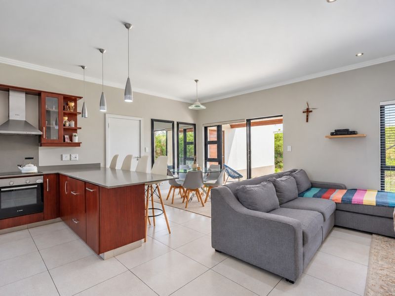 Spacious open-plan living area featuring a modern kitchen with stone countertops, built-in appliances, and seamless flow to the outdoor patio through sliding glass doors.