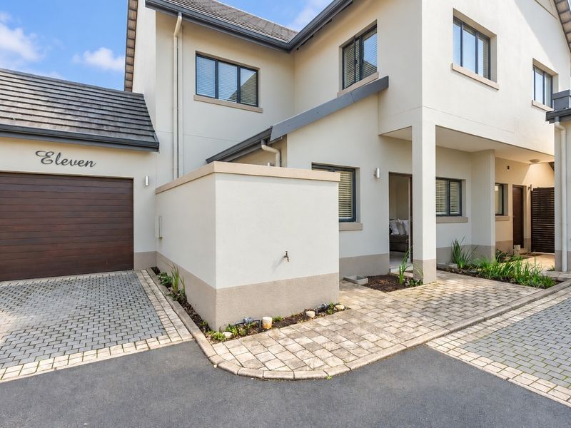Modern townhouse exterior featuring a paved driveway, automated garage, and well-maintained facade with clean architectural lines and neutral finishes.