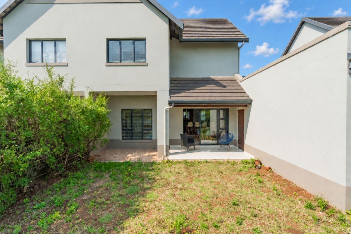 Rear view of the townhouse featuring a paved patio area, sliding glass doors, and a private garden space.