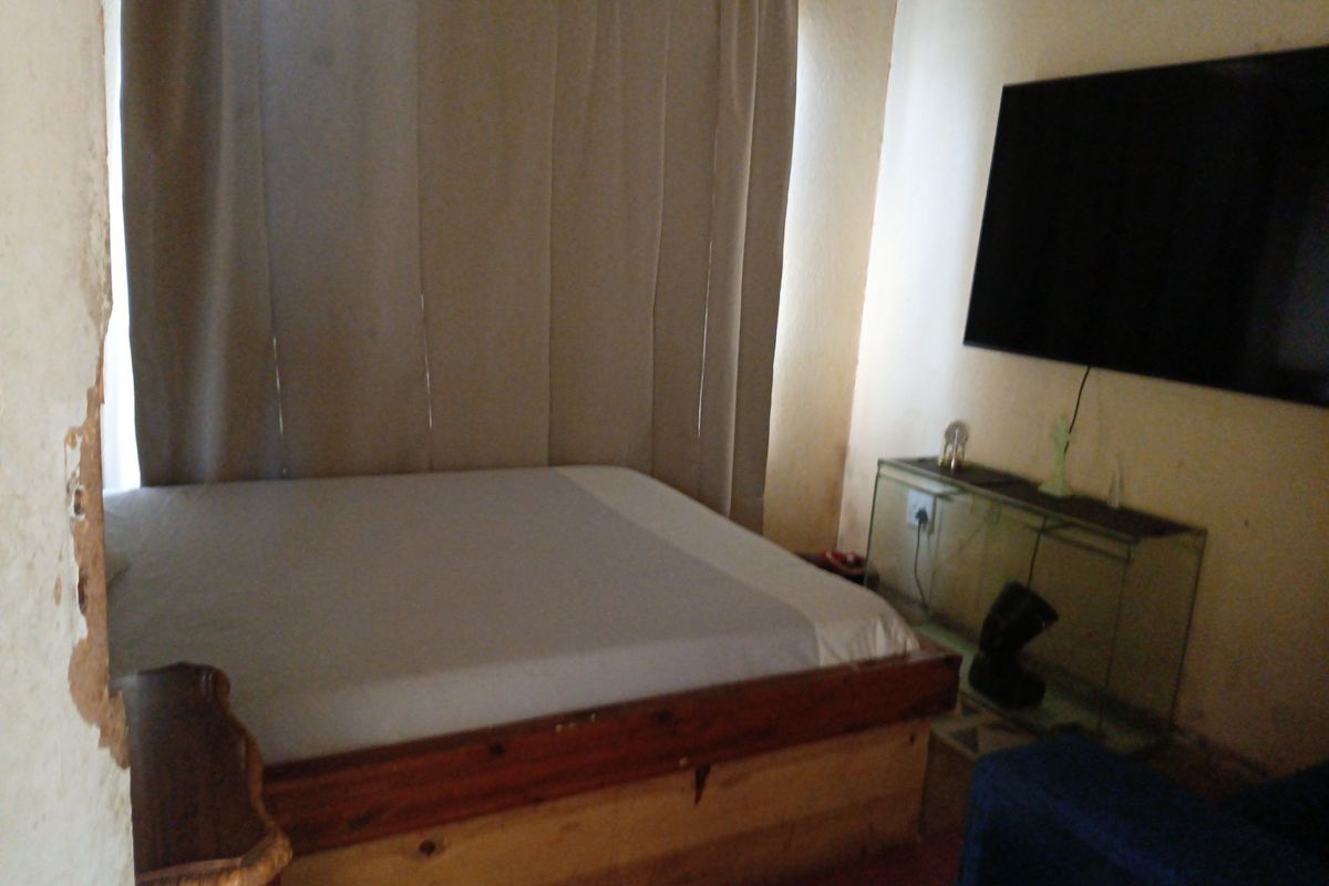 A bedroom featuring visible wall surface damage and peeling paint, requiring maintenance and cosmetic updates to improve the overall condition.