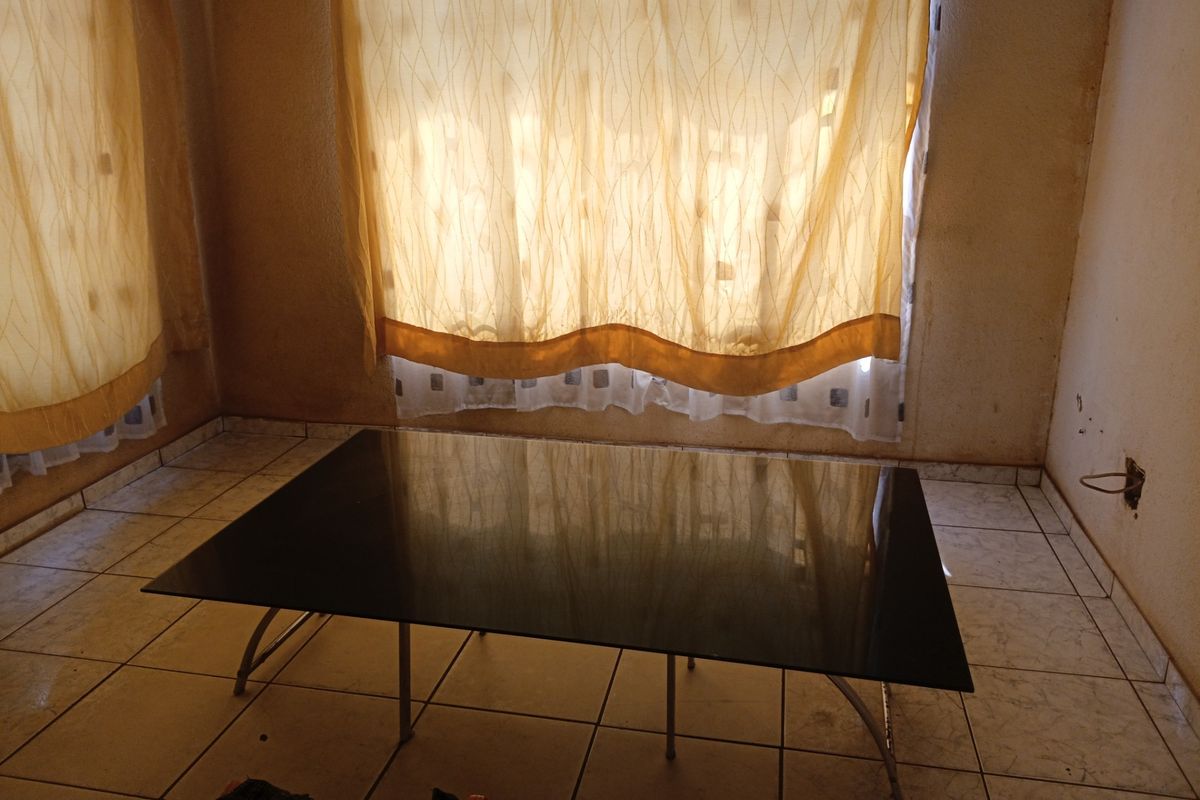 An empty living room featuring ceramic floor tiles and visible wall staining, requiring cosmetic updates and repairs to the wall finishes.