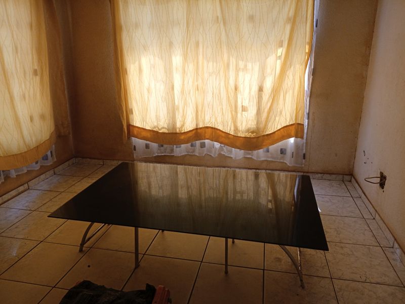 An empty living room featuring ceramic floor tiles and visible wall staining, requiring cosmetic updates and repairs to the wall finishes.