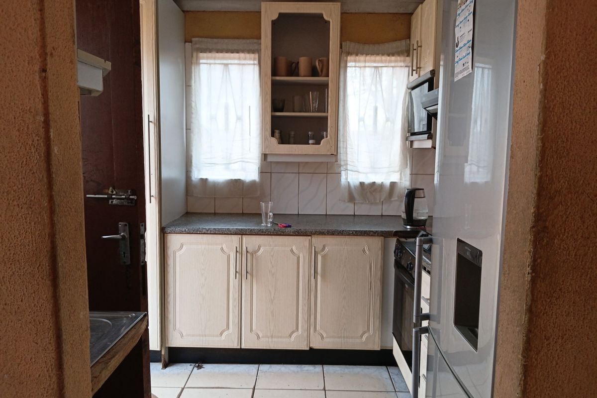 A compact kitchen featuring laminate cabinetry, tiled backsplash, and built-in oven, offering a functional layout in need of cosmetic updates.
