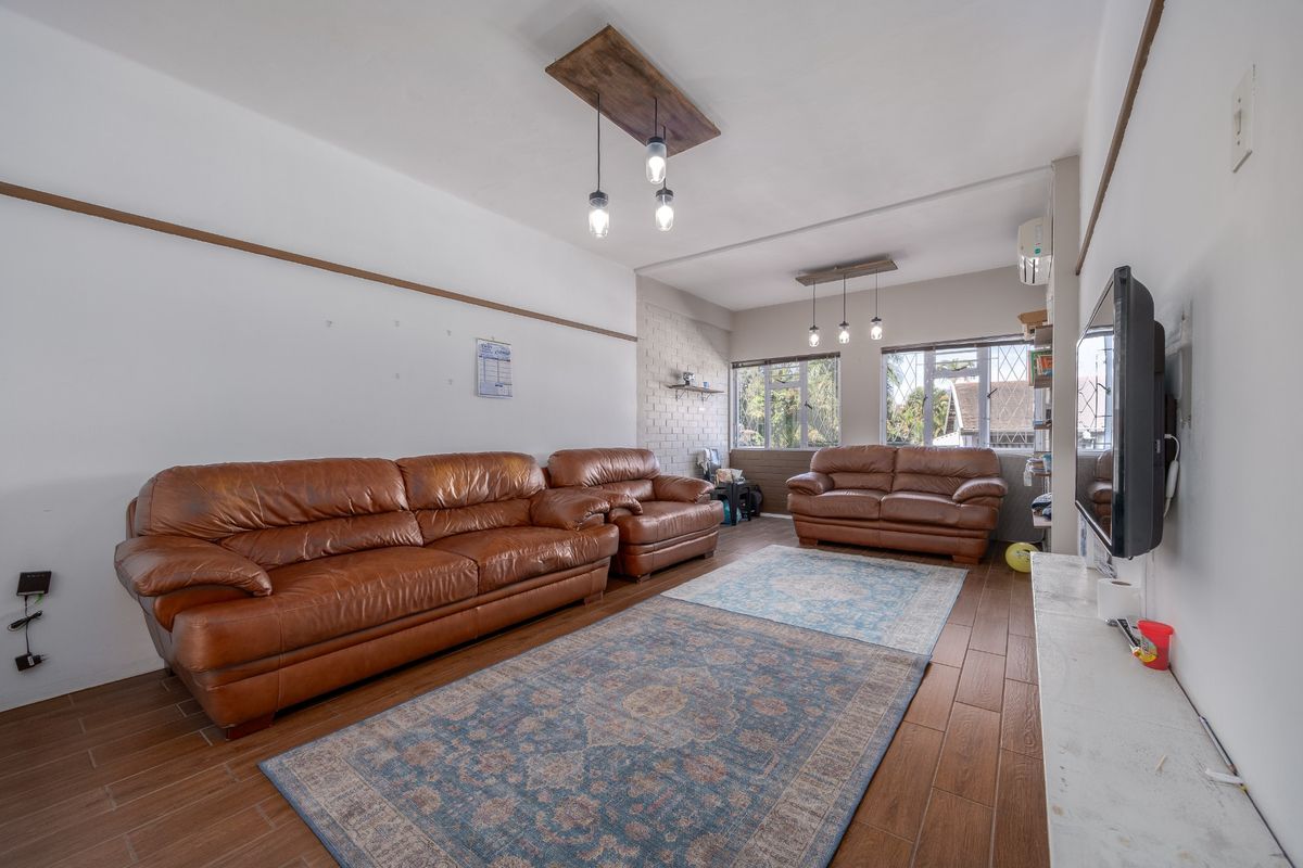 Spacious living room featuring wood-look tile flooring, an exposed brick accent wall, and split-system air conditioning.