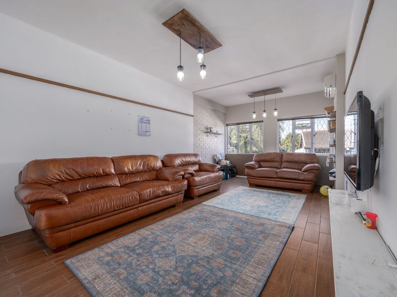 Spacious living room featuring wood-look tile flooring, an exposed brick accent wall, and split-system air conditioning.