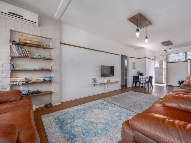 Spacious open-plan living and dining area featuring tiled floors, exposed brick accents, built-in shelving, and modern pendant lighting.