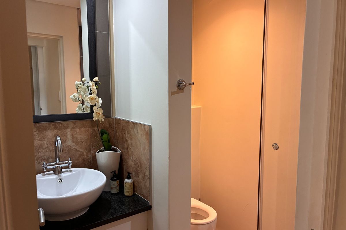 A functional bathroom featuring a modern vessel sink on a granite vanity, a wall-mounted mirror, and a separate toilet area.